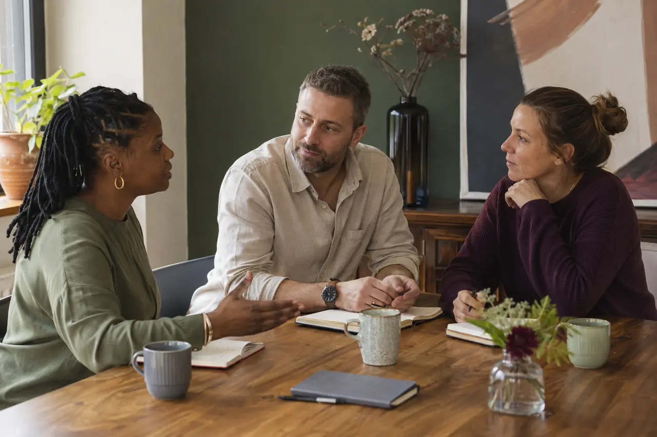Three fictional adult care professionals having a thoughtful team conversation